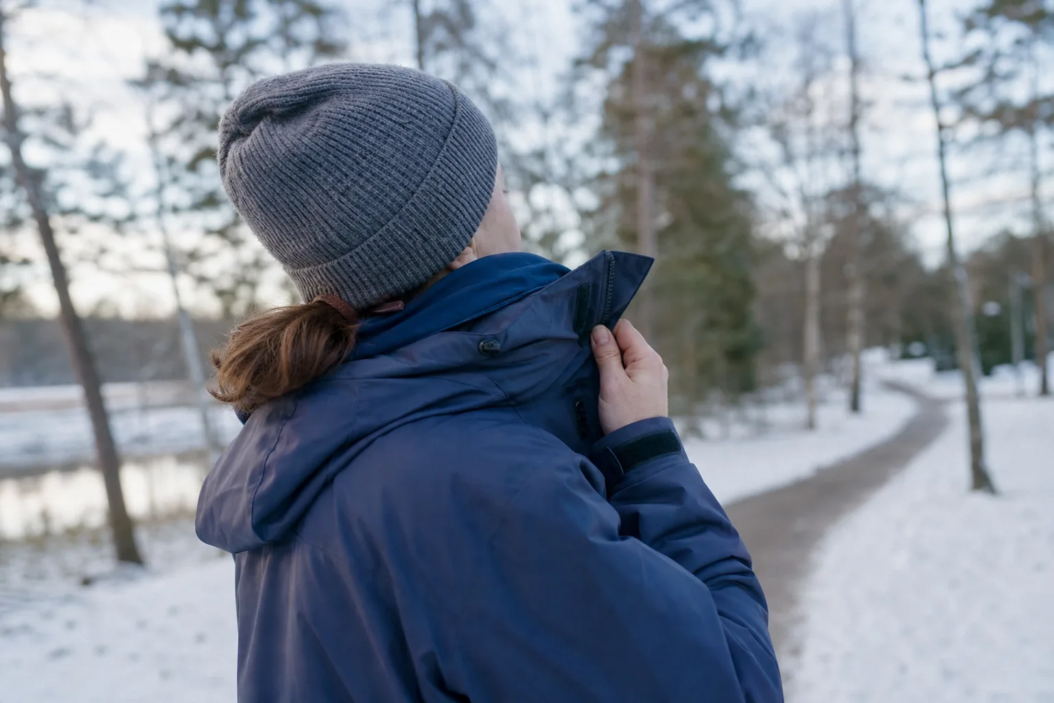 Person på vinterpromenad som öppnar kragen på sin jacka efter rörelse