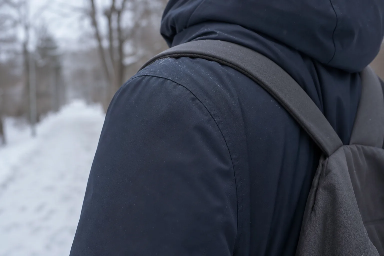 Ryggsäcksrem som ligger över axeln på en mörk vinterjacka
