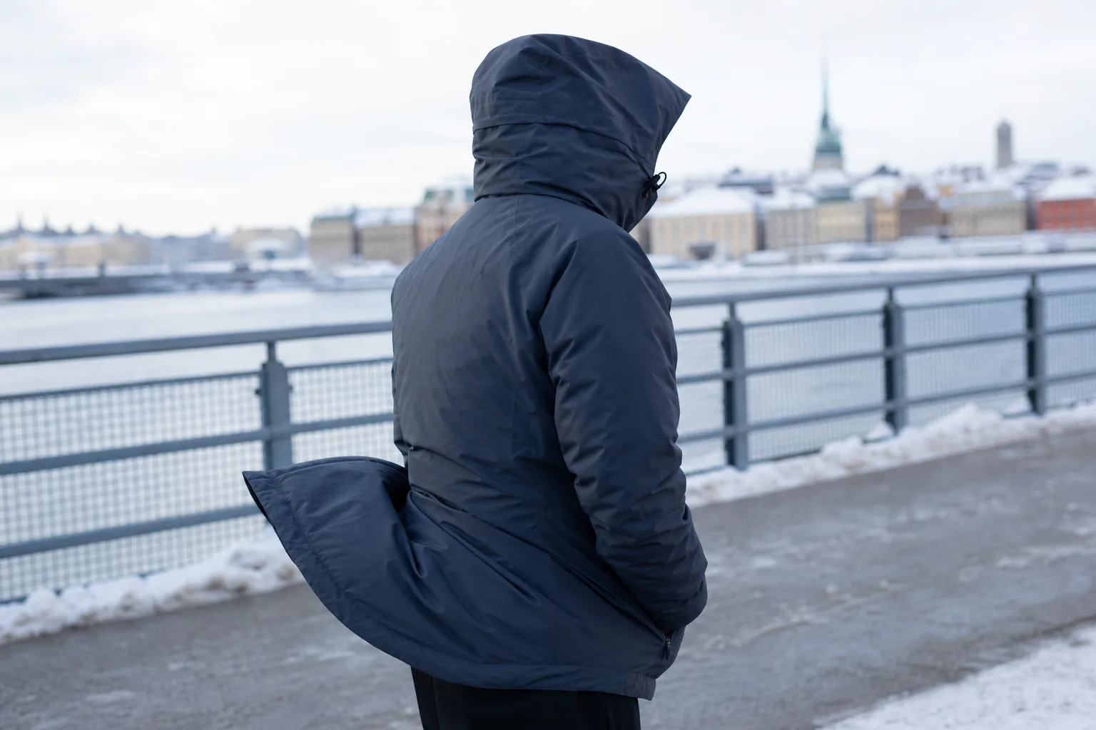 Person i vinterjacka vid en blåsig vinterstrandpromenad
