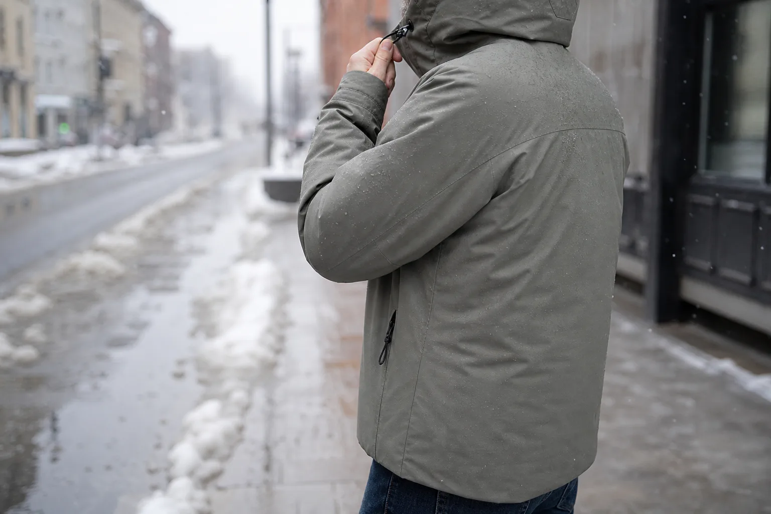 Person i lättare vinterjacka på blöt snöig stadsgata